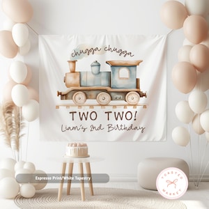 May include: A white tapestry with a watercolor illustration of a train, the text "chugga chugga", and "TWO TWO! Liam's 2nd Birthday". The tapestry is surrounded by balloons and a small table with a cake.