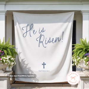 May include: White tapestry with the text "He is Risen!" in blue script, a blue cross, and the Bible verse Matthew 28:6. The tapestry is labeled "Blue Jean Print/White Tapestry". The Toasted Market logo is in the bottom right corner.