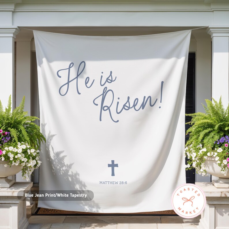 May include: White tapestry with the text "He is Risen!" in blue script, a blue cross, and the Bible verse Matthew 28:6. The tapestry is labeled "Blue Jean Print/White Tapestry". The Toasted Market logo is in the bottom right corner.