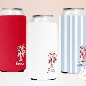 May include: Three can coolers in red, white, and blue striped patterns. Each cooler features a red lobster graphic and a name or title: "Emma", "Bride", and "Allison". The coolers are designed to keep beverages cold.
