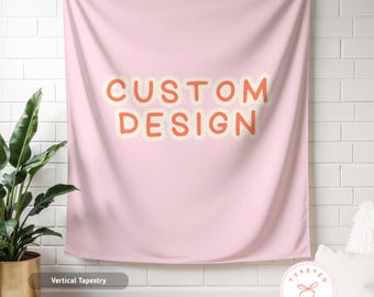 May include: A light pink vertical tapestry with the words "CUSTOM DESIGN" in orange letters with a cream-colored outline. The tapestry is hanging on a white brick wall. A potted plant and a white rug are in the foreground.