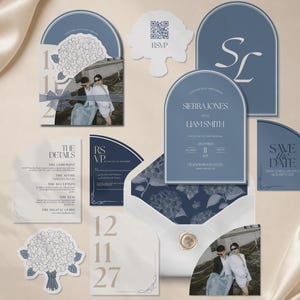 May include: A wedding stationery set in dusty blue and white, featuring arched cards with serif typography, a photo card, a floral-patterned envelope liner, a wax seal, and a QR code RSVP card. Text includes Sierra Jones and Liam Smith.
