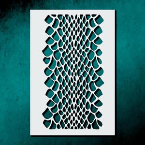 May include: A white stencil with a reptile skin pattern. The design features a series of interconnected, irregular shapes, creating a textured effect. The stencil is rectangular and sits against a teal background.