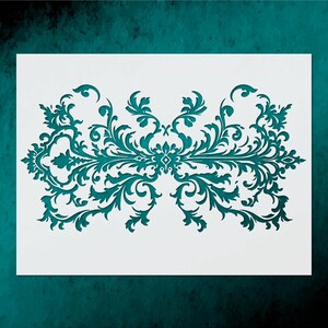 May include: A teal-colored stencil featuring a symmetrical, ornate design with swirling leaves and floral elements. The stencil is cut out of a white rectangular sheet, perfect for decorative painting projects. The background is a dark teal color.