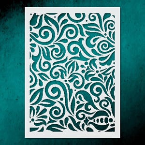 May include: A white stencil with a detailed floral design featuring swirling leaves and flower shapes. The intricate pattern is cut out, revealing a teal background. The design is symmetrical and suitable for various craft projects.