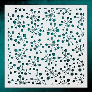 May include: A white stencil with a repeating pattern of teal-colored starburst shapes and circular dots. The design is cut out of the white material, creating a negative space effect. The background is a teal color.