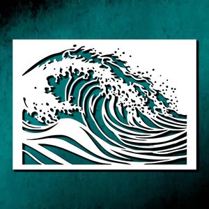 May include: White paper cut-out of a wave against a teal background. The wave design features intricate details, with the crest breaking into small, scattered droplets. The artwork evokes a sense of movement and the power of the ocean.