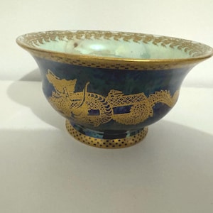 May include: A small blue and green ceramic bowl with gold trim and a dragon design.