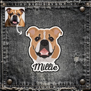 Może przedstawiać: Haftowana naszywka przedstawiająca pysk buldoga w odcieniach brązu, beżu i czerni, z napisem "Millie" w białym skrypcie. Naszywka znajduje się na ciemnym tle dżinsowym, z małym zdjęciem psa w lewym górnym rogu.