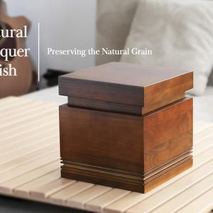 May include: A wooden box with a natural lacquer finish, showcasing the natural grain. The box is a warm brown color and sits on a light-colored wooden surface. Text on the image reads "Natural Lacquer Finish" and "Preserving the Natural Grain."