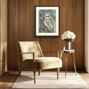 May include: Framed owl art print. The artwork features a detailed watercolor painting of an owl perched on a tree branch. The owl has gray and white feathers and is set against a backdrop of green foliage. The frame is black.
