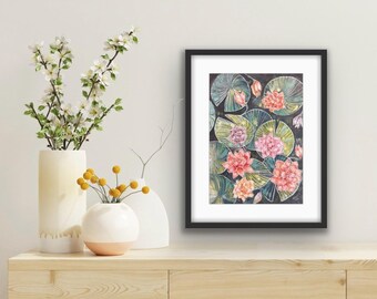 May include: A framed watercolor painting of lily pads and flowers in shades of pink, orange, and green. The artwork is displayed on a wooden surface, with vases of flowers in the foreground.