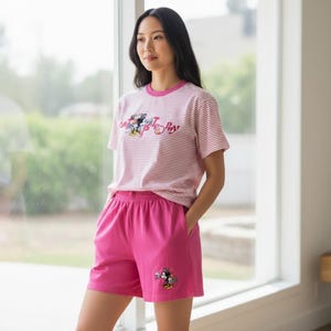 May include: Pink pajama shorts and a striped t-shirt with a Mickey Mouse graphic. The t-shirt has pink and white stripes and the text "A Mickey Story". The shorts are solid pink.