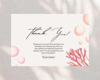 Puede incluir: Una tarjeta de agradecimiento color crema con las palabras "Thank You!" en escritura elegante. La tarjeta incluye un mensaje de gratitud y está decorada con acentos de coral y burbujas rosas estilo acuarela. El nombre "Noa Grace" está en la parte inferior.