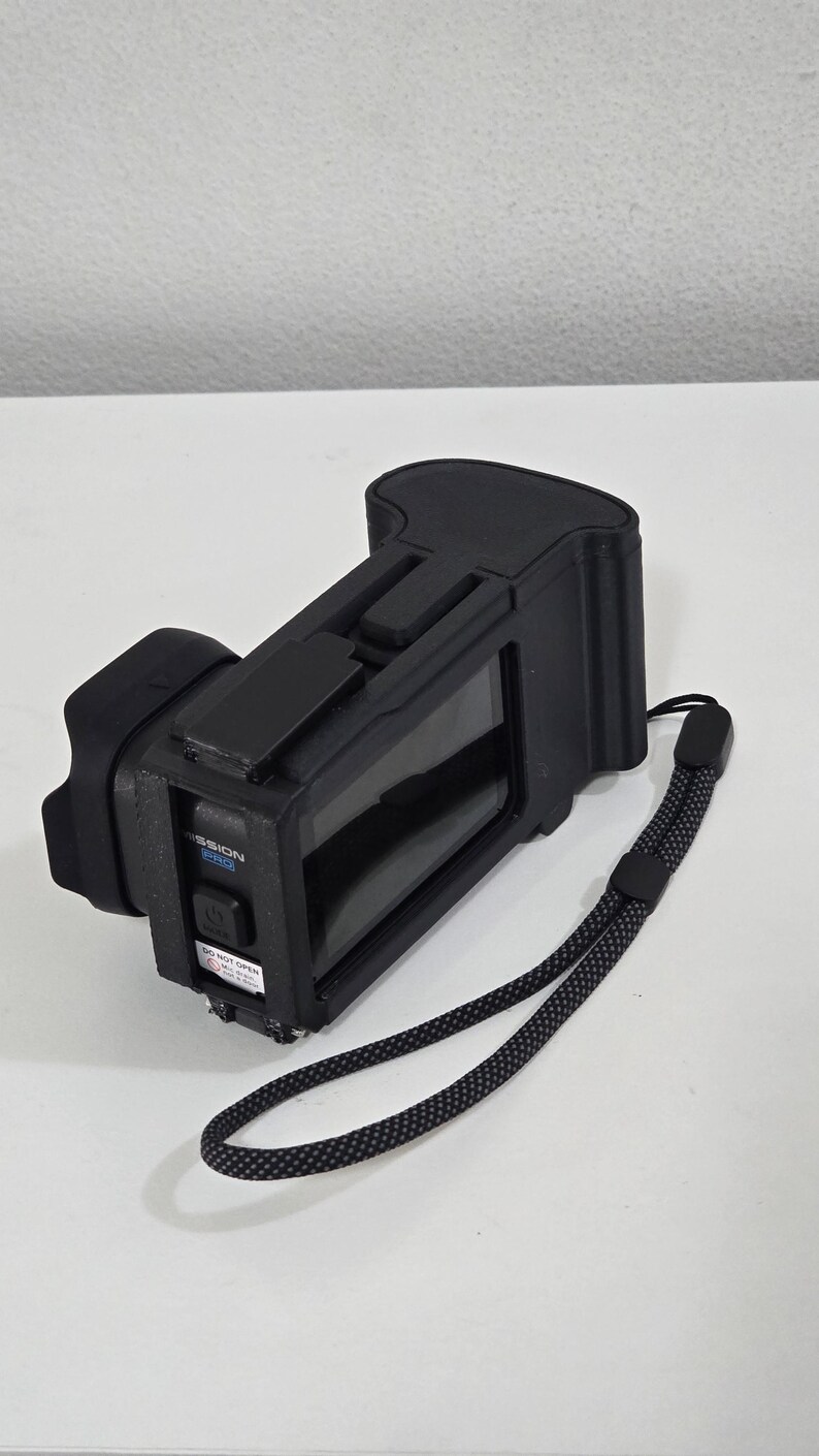 Peut inclure: Un appareil &eacute;lectronique noir avec un &eacute;cran rectangulaire, une poign&eacute;e textur&eacute;e et une dragonne. Le c&ocirc;t&eacute; pr&eacute;sente un bouton d'alimentation, une &eacute;tiquette bleue MISSION PRO et un autocollant d'avertissement blanc DO NOT OPEN en noir.