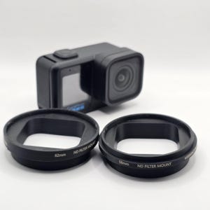 May include: A black action camera positioned behind two circular black ND filter mounts. The left mount is labeled 62mm and the right mount is labeled 58mm. Both mounts feature the text ND FILTER MOUNT printed in white on their outer edges.