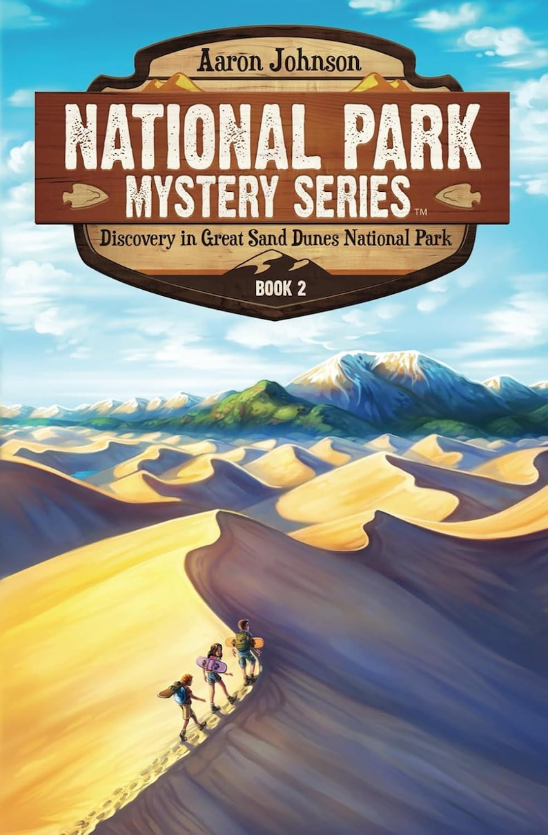May include: Book cover featuring a colorful illustration of sand dunes with a mountain range in the background. Four people are walking up a sand dune. The title of the book is "National Park Mystery Series: Discovery in Great Sand Dunes National Park, Book 2".
