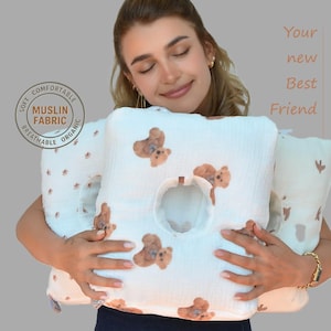 Pode incluir: Almofada de tecido de musselina branca com padrão de ursinho de pelúcia castanho. A almofada tem uma abertura central e está rotulada como "Soft, Comfortable, Breathable, Organic Muslin Fabric". O texto "Your new Best Friend" também é visível.