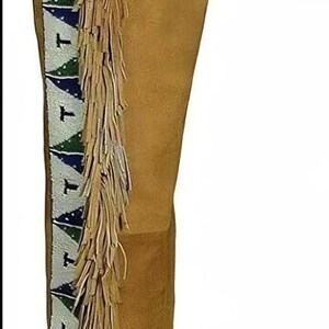 May include: Tan suede pants with decorative fringe along the side. The pants feature a beaded design in white, green, and blue. The pants have a belt loop and a straight leg design.