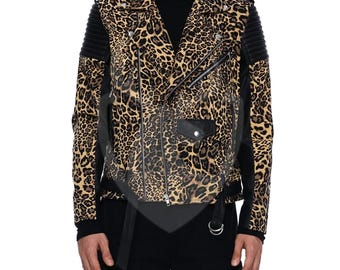 May include: A leopard print motorcycle jacket with black leather accents. The jacket features a classic asymmetrical zipper, a small pocket, and a belt. The sleeves have black quilted panels. The jacket is a mix of tan, brown, and black.