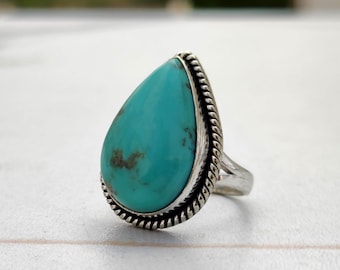 May include: A turquoise teardrop-shaped ring set in sterling silver with a rope-like border.