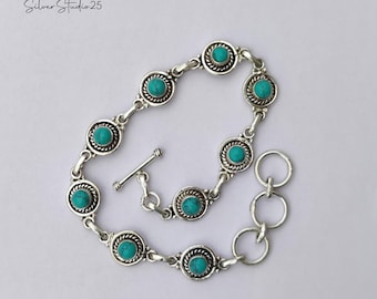 May include: Silver bracelet featuring turquoise-colored stones set in a silver metal. The bracelet has a toggle clasp and is composed of circular links with decorative edging. The text "Silver Studio 25" is in the upper left corner.