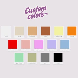 Op de afbeelding: Een kleurenpalet met 15 kleurstalen, elk gelabeld met een kleurnaam. Kleuren zijn onder meer wit, cr&egrave;me, lichtbruin, bruin, lichtgeel, oranje, rood, roze, felroze, lavendel, lichtblauw, mintgroen, pistachegroen, grijs en zwart. De tekst "Custom colors" staat bovenaan.