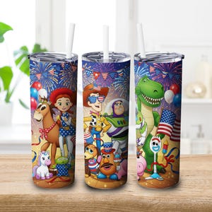 May include: Three stainless steel tumblers with white straws, featuring a patriotic design with characters from the Toy Story movie. The design includes fireworks, flags, and balloons, with a wooden table in the foreground.
