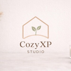 K&ouml;nnte beinhalten: Minimalistisches Logo f&uuml;r Cozy XP Studio, mit einer Hausumriss mit Bl&auml;ttern im Inneren. Das Logo ist in Braunt&ouml;nen gehalten, mit dem Text "Cozy XP STUDIO" darunter. Eine Vase mit getrockneten Pflanzen, eine brennende Kerze und ein Kristall sind ebenfalls im Bild.