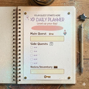 Puede incluir: Un planificador diario XP con espiral abierto, con el texto "YOUR QUEST STARTS HERE" y "Level up your day!". Incluye secciones para "Main Quest", "Side Quests" y "Notes/Inventory". El planificador está sobre una superficie de madera.