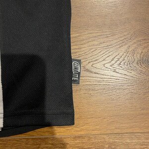 May include: Black athletic shirt with a white stripe and the "CLIMALITE" tag. The shirt has a textured surface and is made of a breathable material. The shirt is likely designed for sports or physical activity.