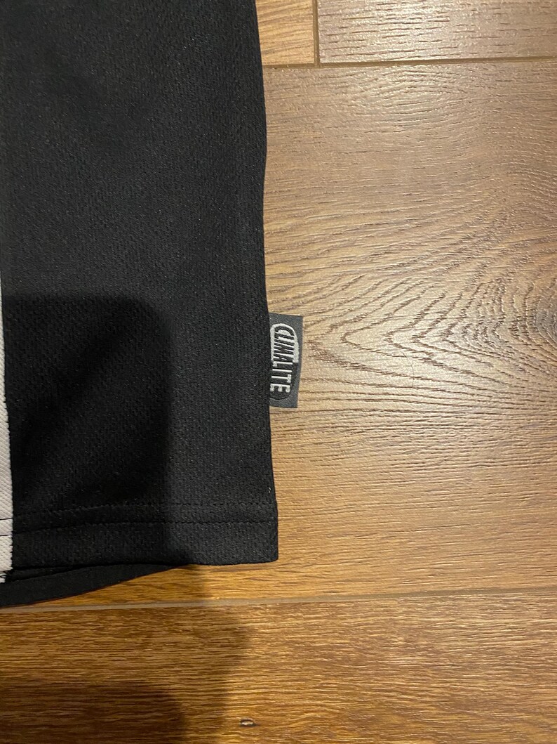 May include: Black athletic shirt with a white stripe and the "CLIMALITE" tag. The shirt has a textured surface and is made of a breathable material. The shirt is likely designed for sports or physical activity.