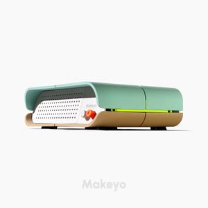 Peut inclure: Un appareil rectangulaire moderne avec un dessus vert menthe et une base marron clair. L'avant présente un panneau perforé blanc et un petit bouton orange. Le mot "Makeyo" est imprimé sur le côté.