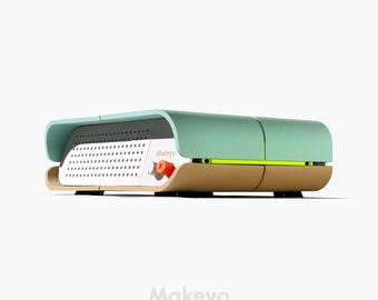 Pode incluir: Um dispositivo retangular moderno com uma parte superior verde menta e uma base castanha clara. A frente apresenta um painel perfurado branco e um pequeno botão laranja. A palavra "Makeyo" está impressa na lateral.