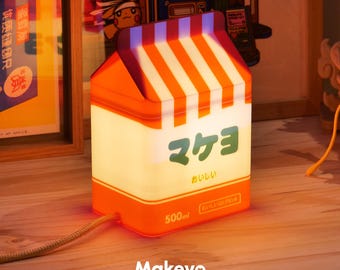 May include: An orange and white milk carton-shaped lamp with Japanese text and a 500ml marking. The lamp has a striped top and a cord. The word "Makeyo" is printed at the bottom.