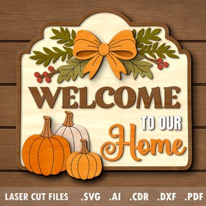 May include: Wooden welcome sign with pumpkins and a bow. The sign reads "WELCOME TO OUR HOME" in brown and orange lettering. The sign has a light-colored background and is decorated with fall foliage. The sign is on a wooden background.