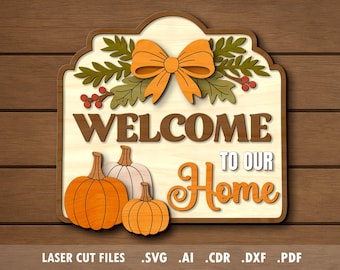Op de afbeelding: Houten welkomstbord met pompoenen en een strik. Het bord leest "WELCOME TO OUR HOME" in bruine en oranje letters. Het bord heeft een lichtgekleurde achtergrond en is versierd met herfstbladeren. Het bord staat op een houten achtergrond.