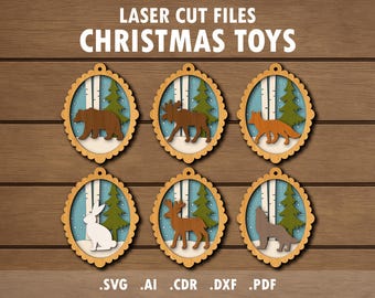 May include: Wooden Christmas toy ornaments with laser-cut designs of a bear, moose, fox, rabbit, deer, and wolf. Each ornament has a scalloped edge and a winter scene with trees. The text "LASER CUT FILES CHRISTMAS TOYS" is at the top.
