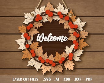 May include: Wooden welcome sign featuring a wreath of fall leaves in shades of cream, orange, and brown, with red berry accents. The word "Welcome" is in white script. The sign hangs from a natural rope against a wooden background.