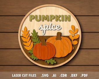 Op de afbeelding: Een houten bord met een cirkelvormig ontwerp met de woorden "PUMPKIN spice" en twee oranje pompoenen. Het bord bevat oranje en groene bladaccenten en is geplaatst tegen een houtnerf achtergrond. De onderkant van het bord luidt "LASER CUT FILES .SVG .AI .CDR .DXF .PDF".