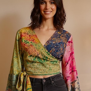 Könnte beinhalten: Ein farbenfrohes Wickeloberteil mit langen Ärmeln. Das Oberteil hat einen V-Ausschnitt und einen Bindverschluss an der Taille. Die Ärmel und der Körper sind aus Patchwork-Stoff in Gelb-, Grün-, Blau- und Rosatönen mit Paisley- und Blumenmustern.