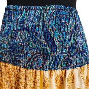 Pu&ograve; includere: Gonna colorata con elastico in vita. La sezione superiore presenta un motivo paisley blu, mentre la sezione inferiore ha un design floreale giallo e crema. La gonna &egrave; realizzata in tessuto leggero.