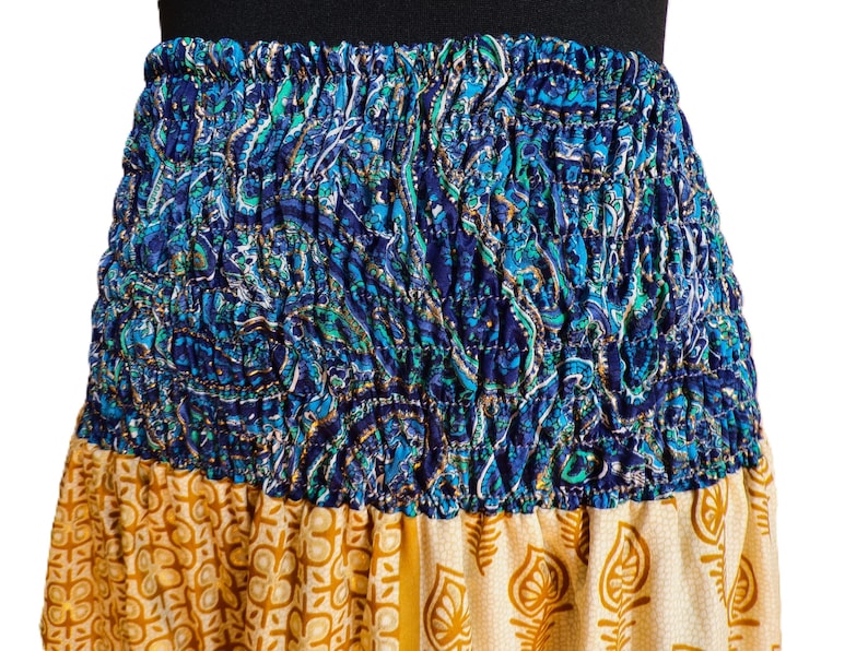 Pu&ograve; includere: Gonna colorata con elastico in vita. La sezione superiore presenta un motivo paisley blu, mentre la sezione inferiore ha un design floreale giallo e crema. La gonna &egrave; realizzata in tessuto leggero.