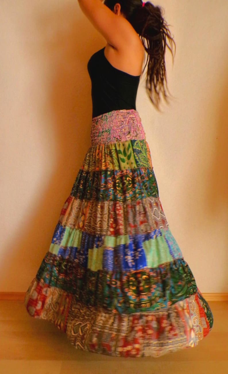 Pu&ograve; includere: Lunga gonna patchwork con un vivace mix di colori e motivi. La gonna presenta un'ampia fascia elastica in vita e un design a balze. Il tessuto della gonna &egrave; un mix di stampe floreali, paisley e geometriche nelle tonalit&agrave; del rosso, blu, verde e oro.