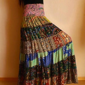 Pu&ograve; includere: Una gonna lunga patchwork con un vivace mix di colori e motivi. La gonna presenta una fascia elastica rosa e un design a balze. Il tessuto include stampe paisley, floreali e geometriche nelle tonalit&agrave; di blu, verde, rosso e giallo.