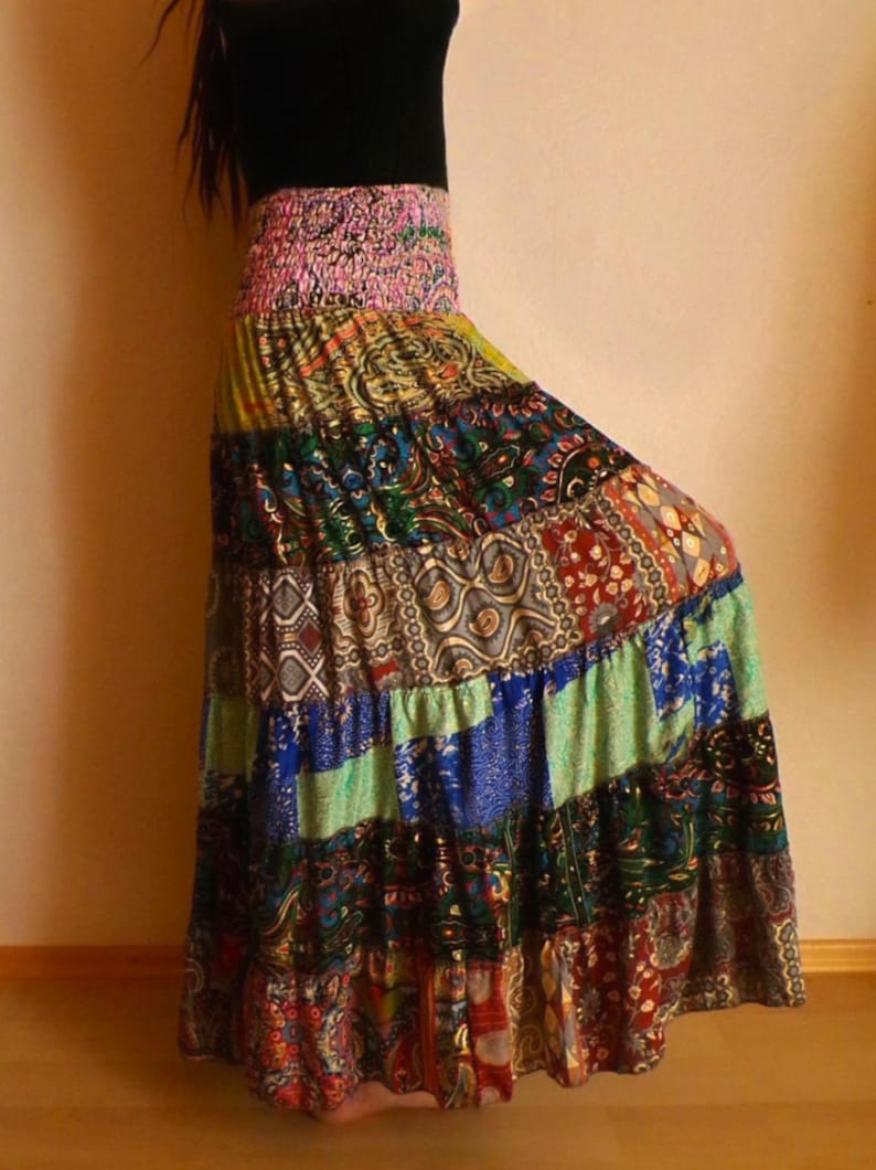 Pu&ograve; includere: Una gonna lunga patchwork con un vivace mix di colori e motivi. La gonna presenta una fascia elastica rosa e un design a balze. Il tessuto include stampe paisley, floreali e geometriche nelle tonalit&agrave; di blu, verde, rosso e giallo.