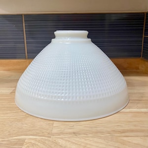 May include: A conical white milk glass lamp shade featuring a raised grid pattern across its surface. The shade has a smooth, circular opening at the top for mounting and a wide, flared base, providing a translucent appearance throughout the piece.