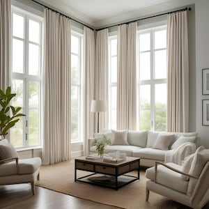 May include: A living room with large windows and white curtains. A white sofa with pillows sits in front of the windows. A coffee table with a black metal frame and a wooden top sits in front of the sofa. A white armchair with a throw pillow sits to the right of the sofa. A floor lamp with a white shade sits in the corner of the room.