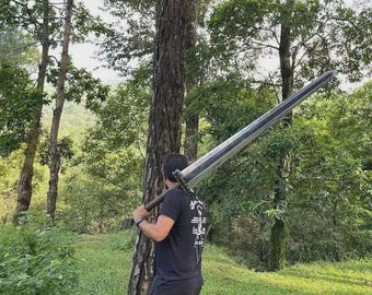 May include: A large, two-handed sword with a wide, silver blade and a dark wooden handle is held over the shoulder. The sword is being carried in a forest setting, with green trees and grass in the background.