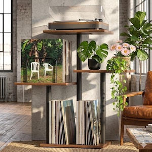 May include: A multi-tiered, dark wood and black metal record player stand with a turntable on top. The stand holds vinyl records and potted plants. A clear cover protects the turntable. The stand is in a room with a brick wall.